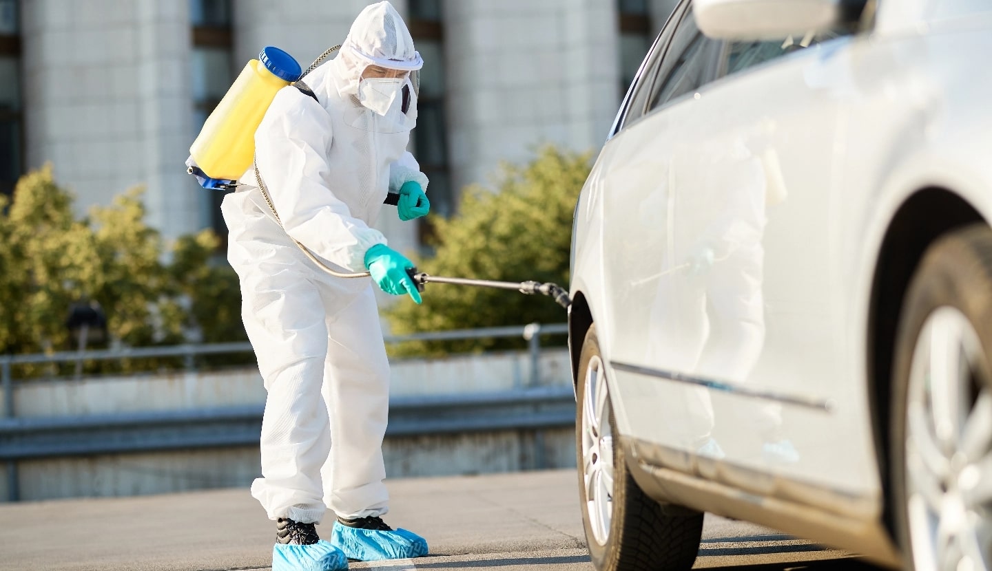 sanitation-worker-protective-suit-spraying-car-tire-city-disinfection-due-covid19-pandemic@2x-min